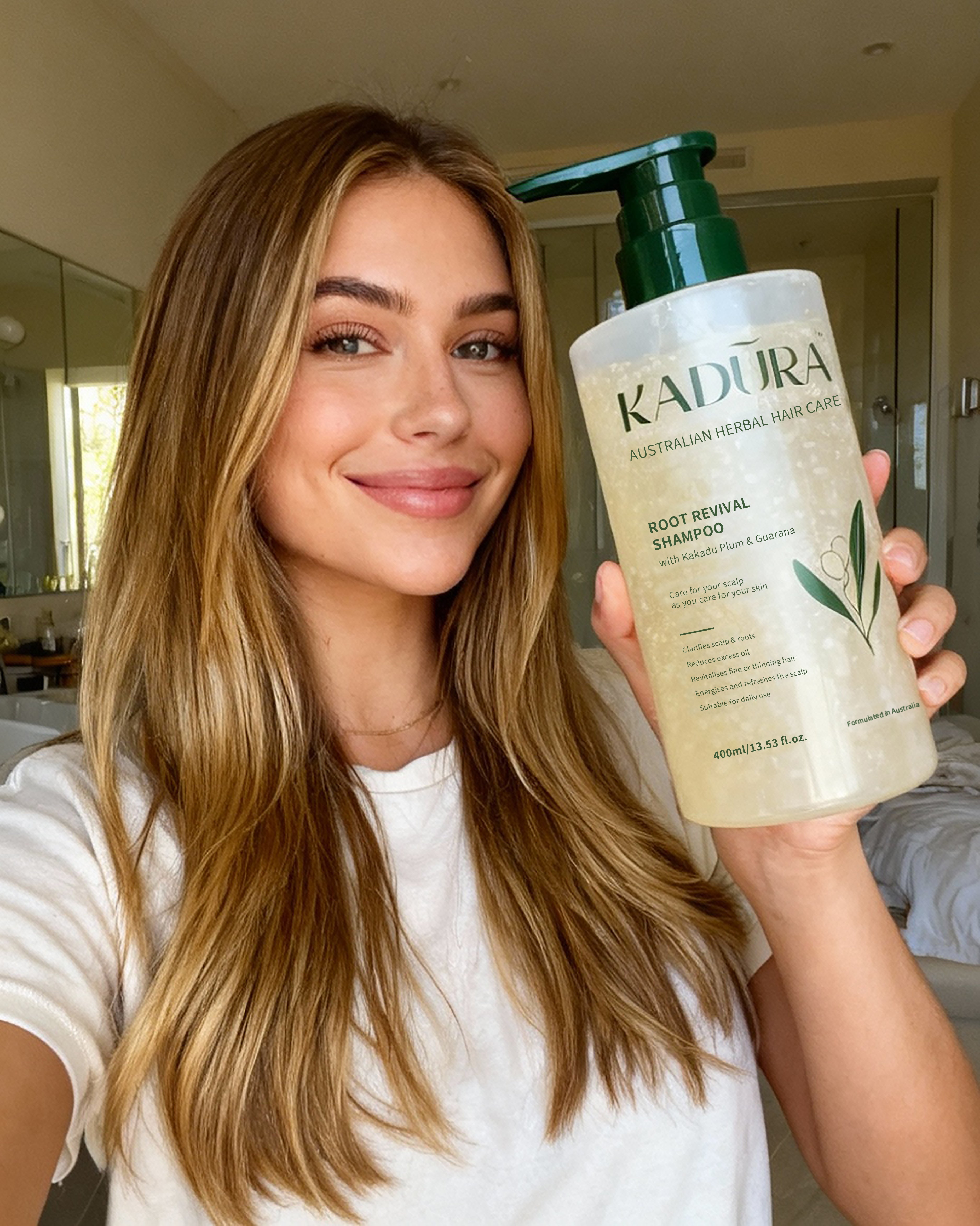 Woman holding a bottle of Kadura shampoo in a bathroom setting