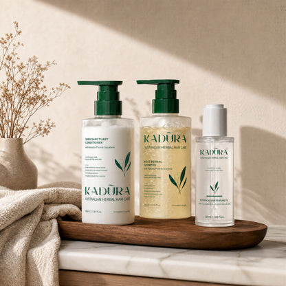 Kadūra CurlDefine Trio for curly hair with shampoo, conditioner and botanical hair perfume oil on a wooden tray