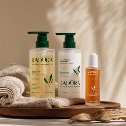 Kadūra RootRevive Scalp Care Trio for hair fall with shampoo, conditioner and scalp serum on a neutral wooden tray